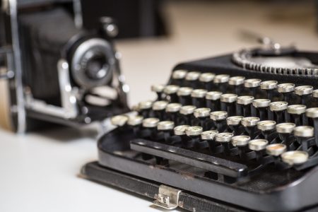 Historical typewriter and camera - artefacts used in the creation of a business history book in the old days and cherished by the team at Canada's leading corporate history agency Historical Branding Solutions Inc.